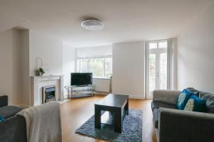 a living room with a couch and a table and a tv at Bright & welcoming garden flat sleeps 6 in style in London