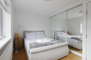 a white bedroom with two beds and a mirror at Bright & welcoming garden flat sleeps 6 in style in London