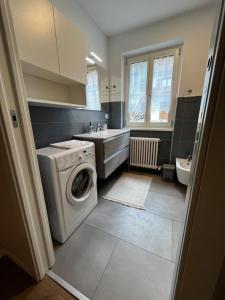 a bathroom with a washing machine and a sink at Trentino Apartments - Casa Laita in Folgaria