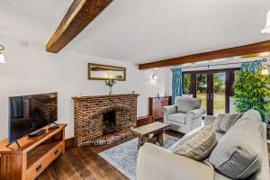 sala de estar con sofá y chimenea en Rustic 5 Bed Farm House in Derbyshire, sleeps 9, 