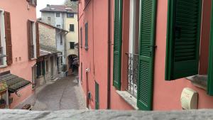 une ruelle étroite avec des volets verts dans un bâtiment dans l'établissement Appartamento Centro Storico Porlezza, à Porlezza