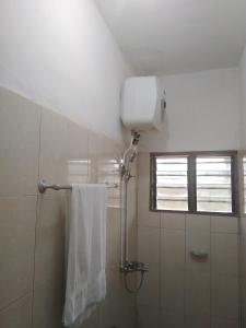a bathroom with a shower with a towel and a window at Bois vert Hôtel in Abomey