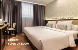 a hotel room with a large bed and a desk at Infinity8 Bali in Jimbaran