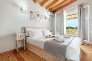 a white bedroom with a bed and a large window at S&K Luxury Μaisonette in Potamós +10 photos
