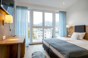een slaapkamer met een bed en een groot raam bij AVALON Hotel Bad Reichenhall in Bad Reichenhall