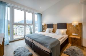 a bedroom with a large bed with a large window at AVALON Hotel Bad Reichenhall in Bad Reichenhall