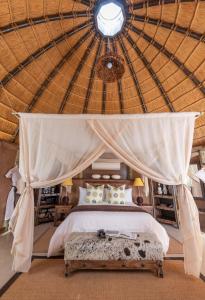 ein Schlafzimmer mit einem Himmelbett in einem Zelt in der Unterkunft Camp Kipwe in Twyfelfontein