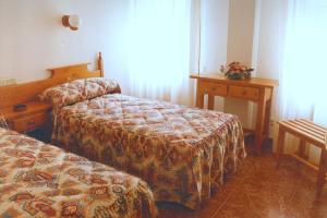 a hotel room with two beds and a table at Hostal Cuatro Esquinas in Ejea de los Caballeros