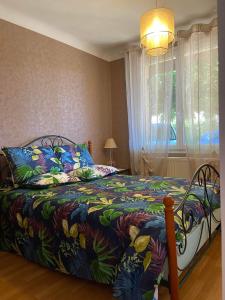 ein Schlafzimmer mit einem Bett mit einer bunten Decke und einem Fenster in der Unterkunft Claire fontaine in Beaumont-du-Périgord