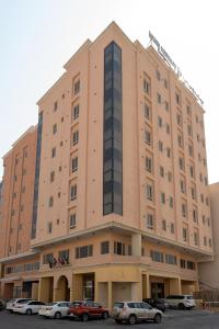 un grand bâtiment avec des voitures garées dans un parking dans l'établissement فخامة الضيافة - Dyafa Luxury, à Khobar