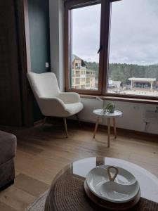 a living room with a table and a chair and a window at Avram in Zlatibor