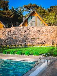 una casa con un muro in pietra e una piscina di Pinhan Otel Kazdağıları a Ayvacık