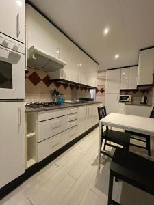eine Küche mit weißen Schränken und einem Tisch darin in der Unterkunft Urgel habitaciones in Barcelona