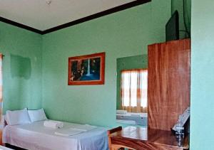 een slaapkamer met groene muren en een bed en een tafel bij RedDoorz at July's Haven Seaside Pension Camiguin in Mambajao