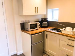 a small kitchen with a microwave and a sink at Deers Leap A modern new personal holiday let in Blakeney