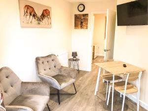 a living room with two chairs and a table at Deers Leap A modern new personal holiday let in Blakeney