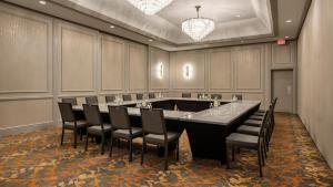Holiday Inn Winnipeg-South, an IHG Hotel في وينيبيغ: قاعة اجتماعات كبيرة مع طاولة وكراسي كبيرة