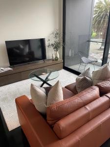 a living room with a leather couch and a glass table at Heart of St Kilda in Melbourne