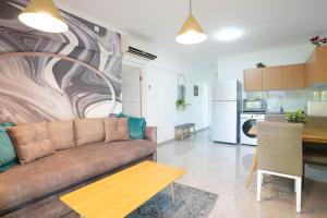 a living room with a couch and a kitchen at YalaRent Royal Park Resort Complex Apartments in Eilat