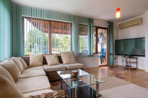 Una sala de estar con un sofá y una mesa de cristal. en Villa ADORA, en Balchik