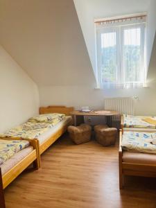 a room with two beds and a table and a window at Zajazd pod Sosnami in Berezka