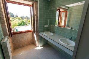 baño de azulejos verdes con lavabo y ventana en A Casa Do Boi, en Amés