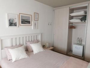 a bedroom with a bed with white sheets and pink pillows at Sea-Me Ostend in Ostend