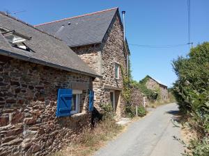 una antigua casa de piedra con una ventana azul en un camino en Maisonnette et gîte proches de la mer, en Plouha