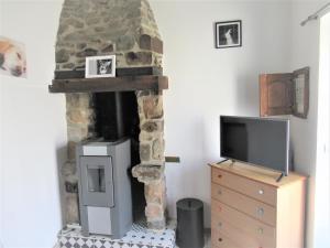 sala de estar con chimenea de piedra y TV en Maisonnette et gîte proches de la mer, en Plouha