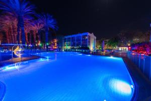 a large swimming pool at night with palm trees at YalaRent Royal Park Resort Complex Apartments in Eilat