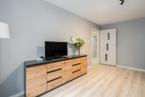 una sala de estar con TV de pantalla plana en una cómoda de madera en Family Apartment Poznań Rataje by Renters en Poznan