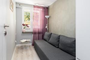 a living room with a gray couch and a window at Family Apartment Poznań Rataje by Renters in Poznań