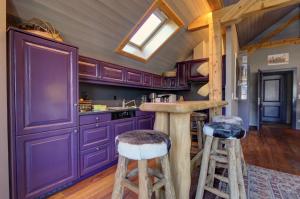 uma cozinha com armários roxos e bancos de madeira em Appartement La Gentiane 63 em Chateau-d'Oex