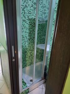 una doccia con porta in vetro e piastrelle verdi di Sorrento Relais a Sorrento