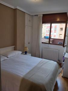 Un dormitorio con una gran cama blanca y una ventana en MONTE NARANCO-LOS VEGA PARKING e INTERNET GRATIS, en Oviedo