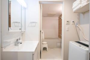 Baño blanco con lavabo y aseo en Minn Kamata en Tokio