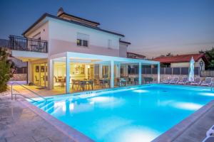 a swimming pool in front of a house at Cool Šilo Appartement Resort in Šilo