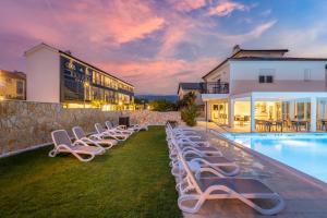 a row of lounge chairs next to a swimming pool at Cool Šilo Appartement Resort in Šilo