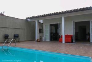 una casa con piscina frente a ella en Pousada da Sú en Bertioga