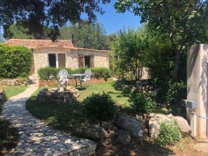 un jardín con 2 sillas y una mesa y un edificio en Stunning Cottage with Pool in Provence France, en Lorgues