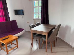 sala de estar con mesa y sofá púrpura en Ege Apartments, en Yalıkavak