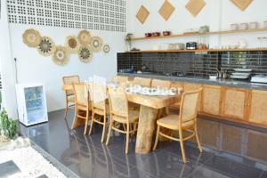 a kitchen with a wooden table and chairs at Pringgading Surf Camp Mitra RedDoorz in Bengkulu
