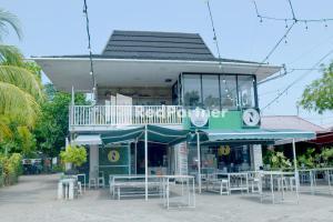 un restaurante con mesas y sillas frente a un edificio en Pringgading Surf Camp Mitra RedDoorz en Bengkulu