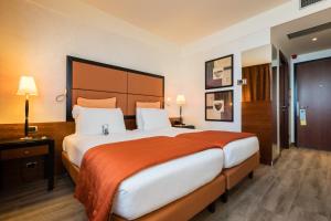 een slaapkamer met een groot bed en een oranje deken bij Crowne Plaza Milan - Malpensa Airport, an IHG Hotel in Case Nuove