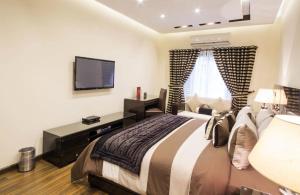 a bedroom with a large bed and a television at Royaute Luxury Suites and Hotel Gulberg Lahore in Lahore