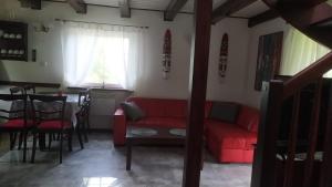 - un salon avec un canapé rouge et une table dans l'établissement 4 Pory Kaszub - Domek z banią i sauną, à Skoszewo