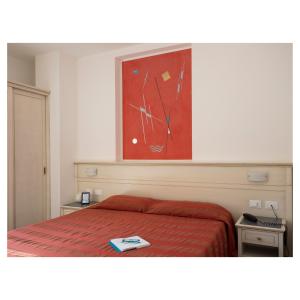 a bedroom with a bed with a red blanket and a painting at Hotel Margherita in Monterosso al Mare