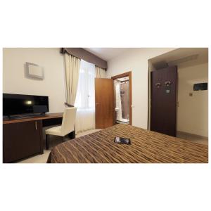 Cette chambre comprend un lit, un bureau et une télévision. dans l'établissement Hotel Margherita, à Monterosso al Mare