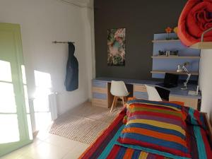 una camera da letto con una scrivania e un letto con una coperta colorata di Pis amb encant a Campdevànol,al centre del poble. a Campdevánol