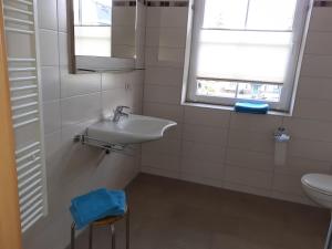 ein weißes Badezimmer mit einem Waschbecken und einem Spiegel in der Unterkunft Ferienwohnung - August-Bebel-Str. 19 in Oelsnitz